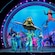Goofy y Crush con un grupo de artistas en el escenario durante un espectáculo de Disney Seas the Adventure